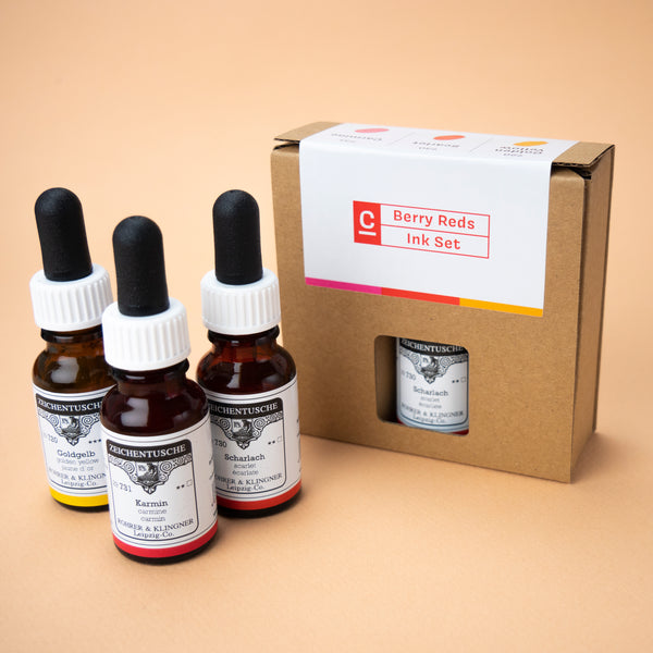 A photo of the Berry Reds ink set in its box, with all three bottles next to it. The box has a small hole through which the label on the color scarlet can be seen.