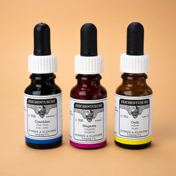 A photo of all three ink bottles included in this set next to one another: cyan blue, magenta, and yellow. The bottles are made from dark brown glass with white labels and a black rubber cap.