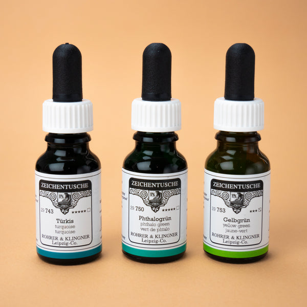 A photo of all three bottles included in this set next to each other: turquoise, phthalo green, and yellow green. The bottles are made of dark brown glass with white labels and black rubber caps.