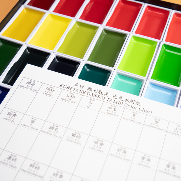 Closeup photograph of a watercolor set with 48 different colors, against a peach colored background.