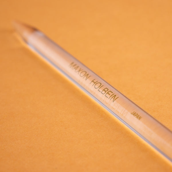 Photograph of a clear plastic burnishing tool, against a peach colored background.