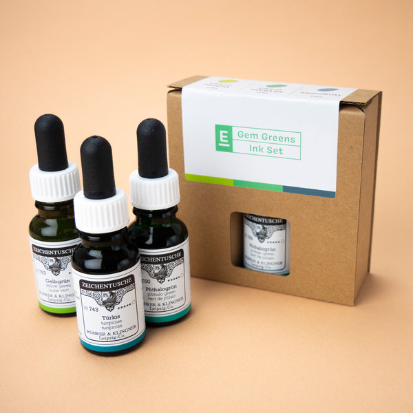 A photo of the Gem Greens ink set in its box, with all three bottles next to it. The box has a small hole through which the label of the color phthalo green can be seen.