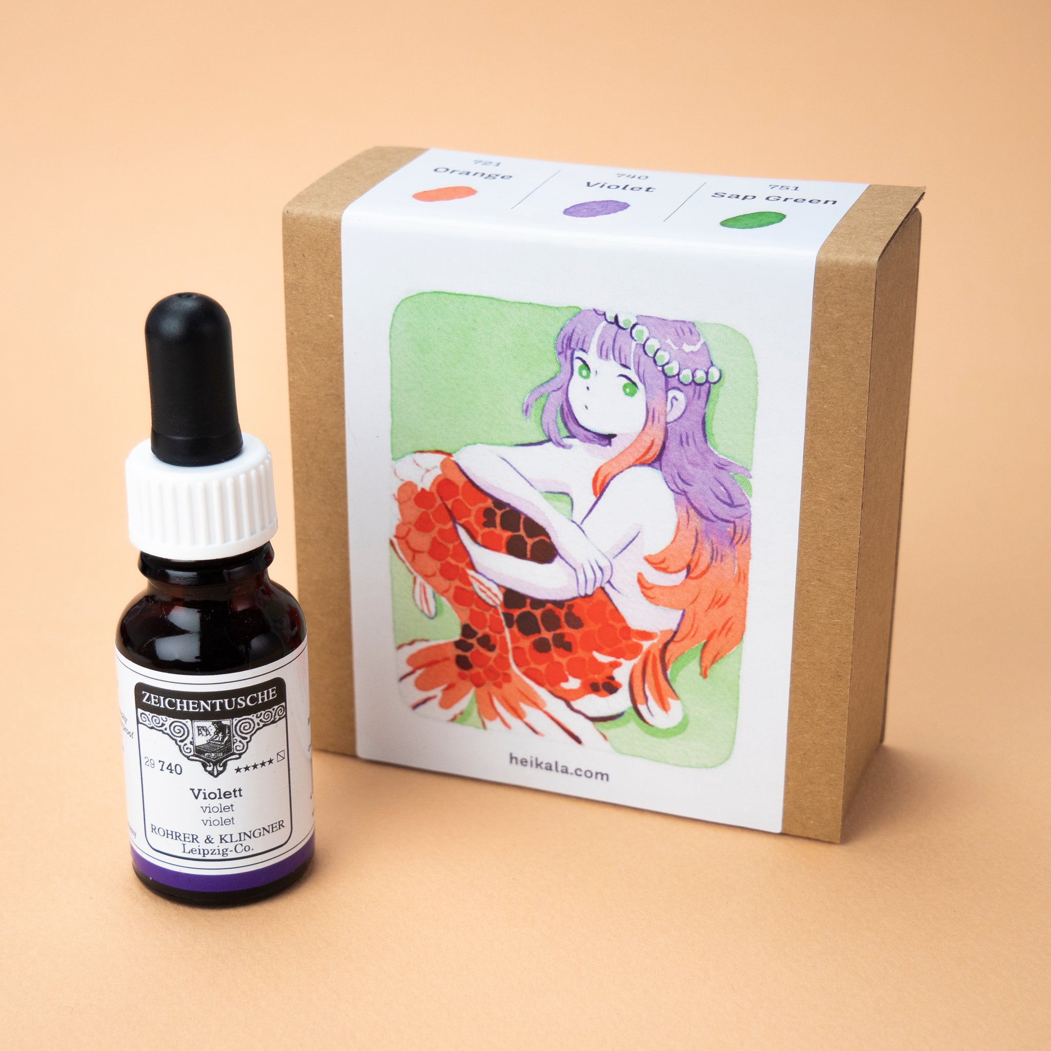 A photo of the Complementary Colors ink set in its box, with a single bottle of the color violet next to it. The label on the box is a painting of a koi mermaid with purple and red hair and a string of pearls on her head.