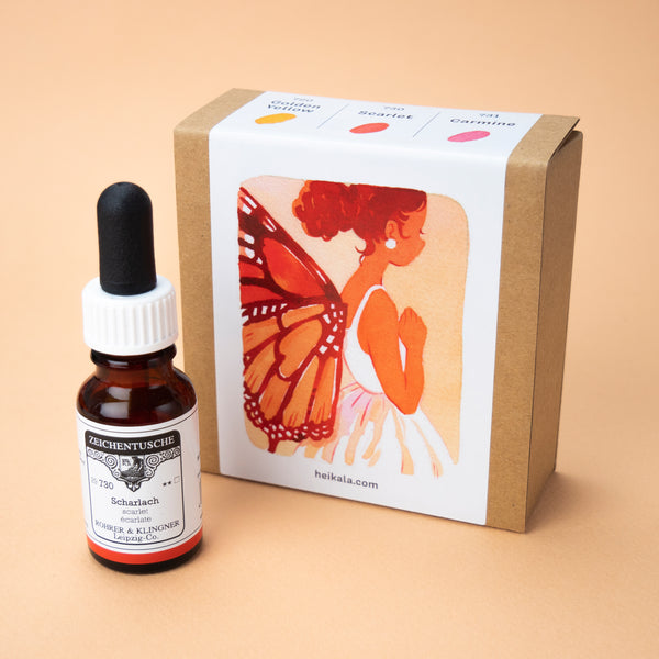 A photo of the Berry Reds ink set in its box, with one bottle of the color scarlet next to it. The label on the box is a painting depicting a fairy with butterfly wings, wearing a white dress and pearl earrings.