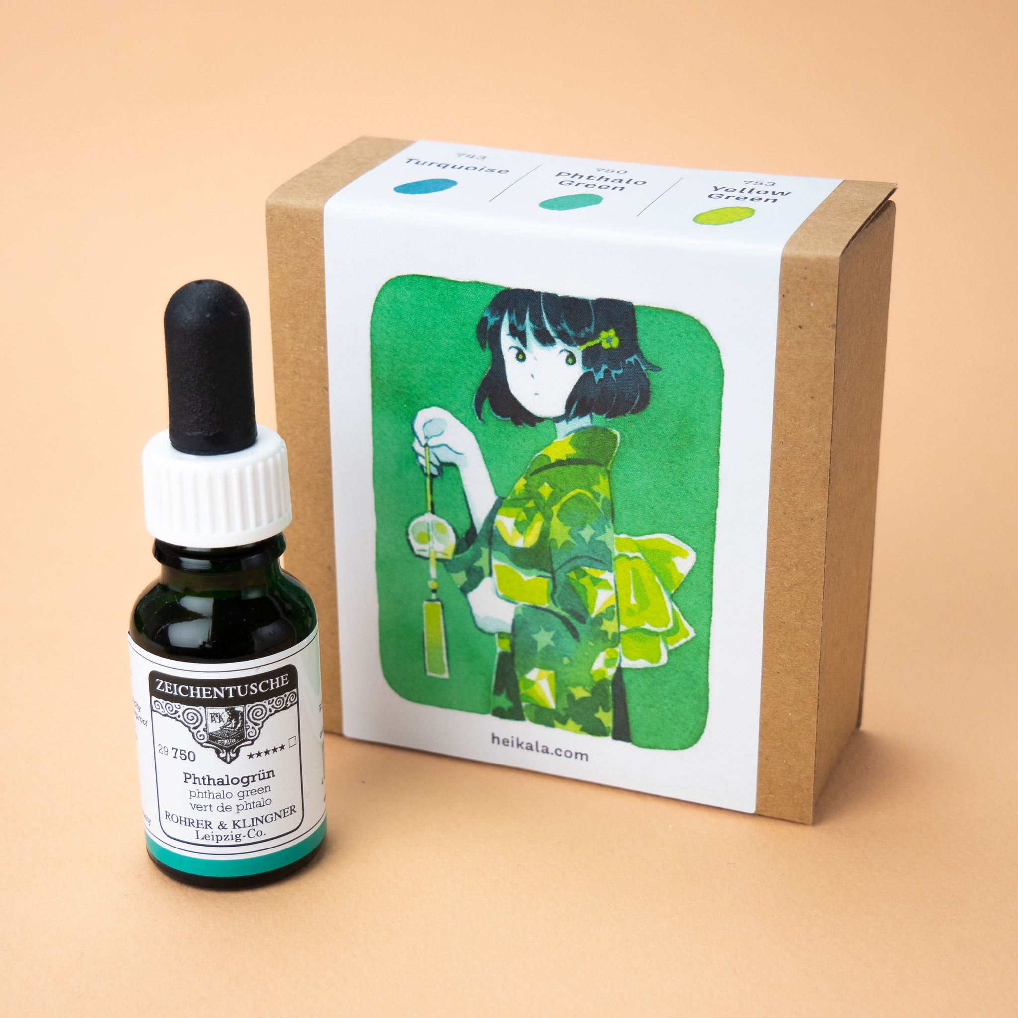 A photo of the Gem Greens ink set in its box and single bottle of the color phthalo green next to it. The label on the box is a painting depicting character wearing a green yukata holding a glass wind chime.
