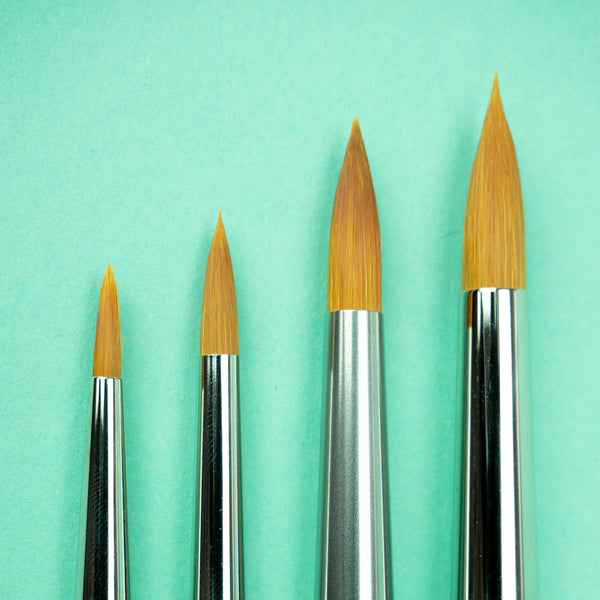 A closeup photo of the bristles on all the available brush sizes against a turquoise background, with size 0 on the left and size 6 on the right.