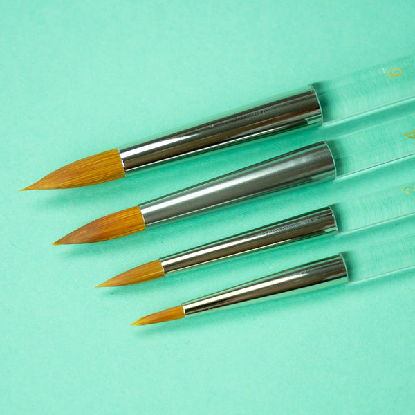 A closeup photo of all the different brush sizes in a row by size, with size 6 on top and size 0 on bottom, against a turquoise background.
