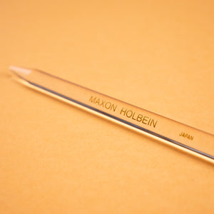 Photograph of a clear plastic burnishing tool, against a peach colored background. 